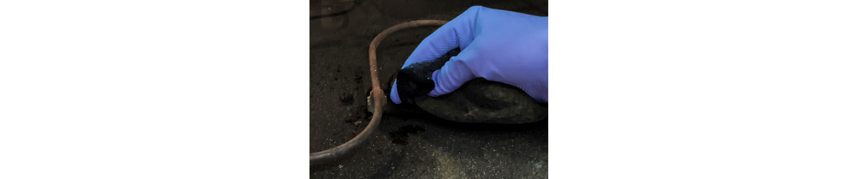 Close-up of hand in blue glove cleaning around heating coils of oven cavity