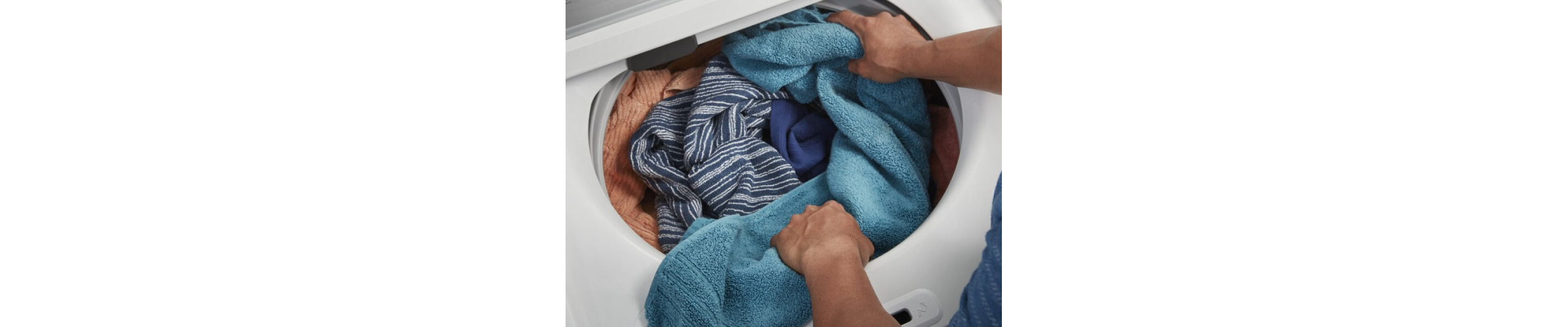 A person adding towels to a Maytag® top load washer