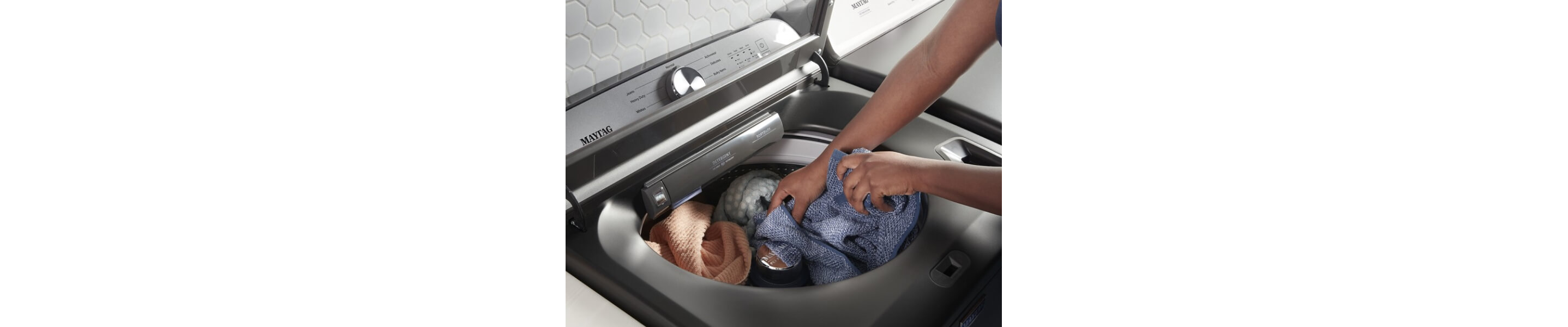 A person adding laundry to a Maytag® top load washer