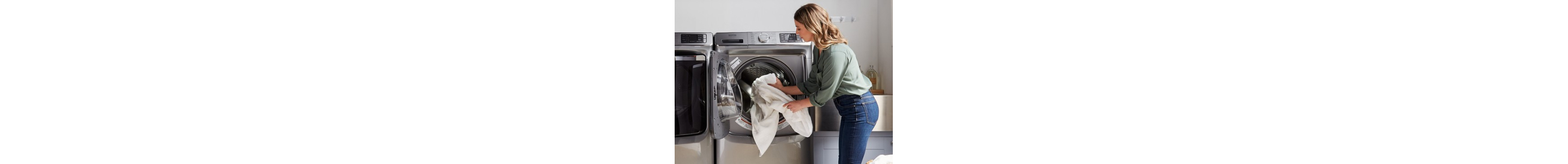 Person loading white blanket into dryer