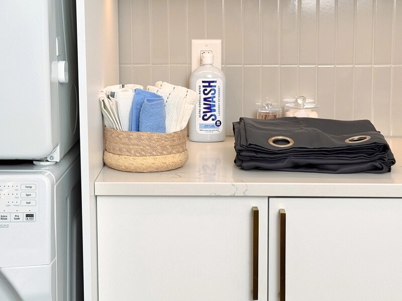 A folded curtain with Swash ® laundry detergent on a white marble counter