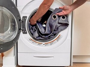 Arms putting a gray curtain with rungs into a front load washer