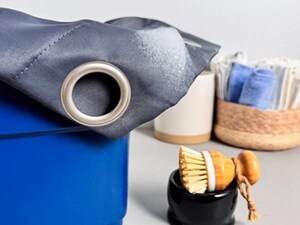 A blue curtain with a rung in a bucket next to a small scrub brush