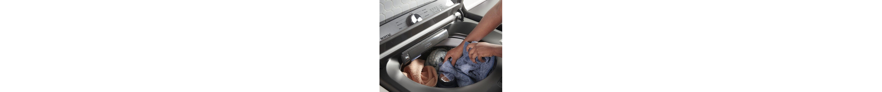 Hands loading laundry into the washer