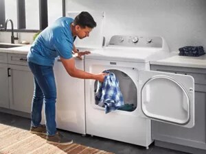  A man pulling a shirt out of the dryer