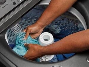 Someone holding a shirt in the washer as the water flows in