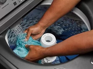 Someone holding a shirt in the washer as the water flows in