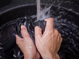 Someone hand washing a clothing item in a stream of water inside a washer
