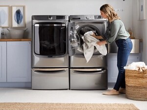 A person removing clothes from a silver front load dryer