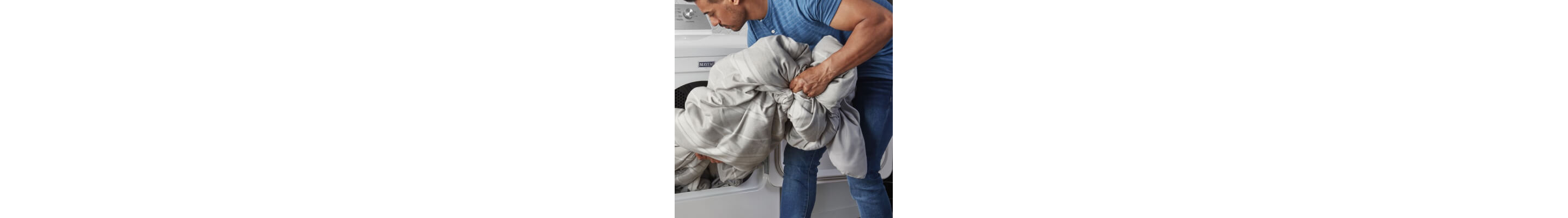 Person removing blanket from white Maytag® dryer