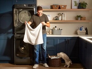 Person folding laundry next to a cat in a laundry room