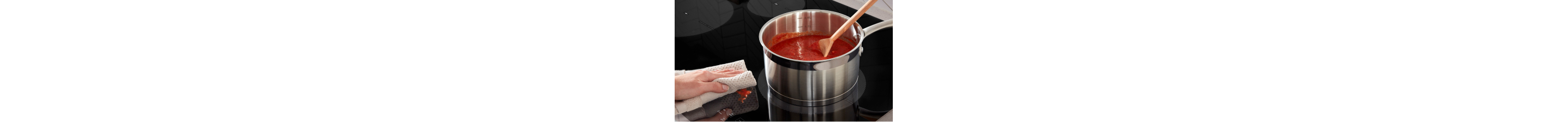  Red sauce in a pan on induction cooktop with a hand wiping a small splatter