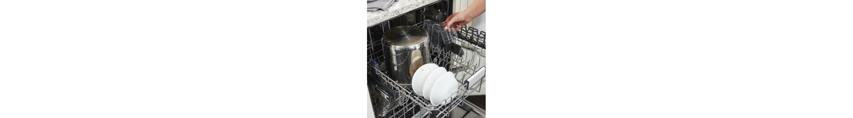 Person loading cups into the top rack of a dishwasher
