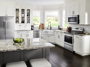 A kitchen with white cabinets, stainless steel appliances and counter seating