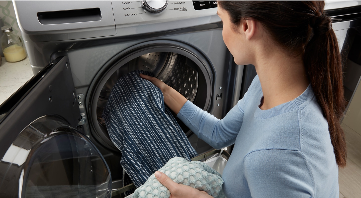 Woman loading towels into a front-load washing machine