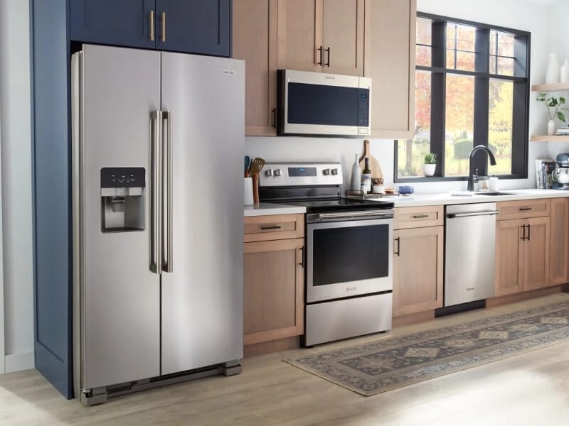 Stainless steel Maytag® side-by-side refrigerator in brown cabinetry