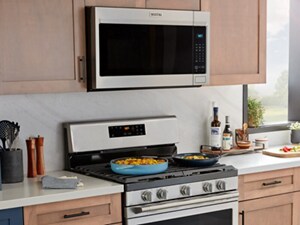 Maytag® over-the-range microwave above a Maytag® gas range with food cooking on the stovetop