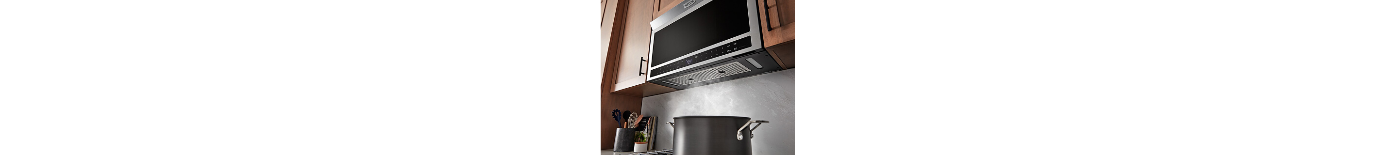 Water boiling in pot as over-the-range microwave vents air above