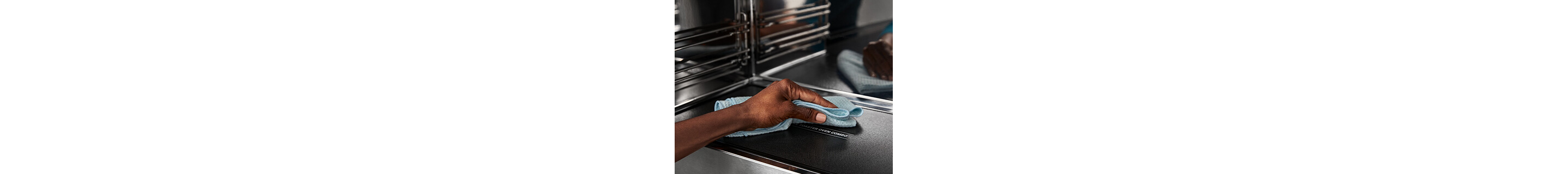Person wiping the interior of a turntable-free microwave