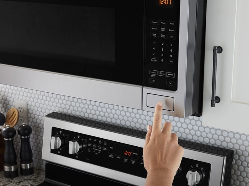 Person pressing button to open an over-the-range microwave
