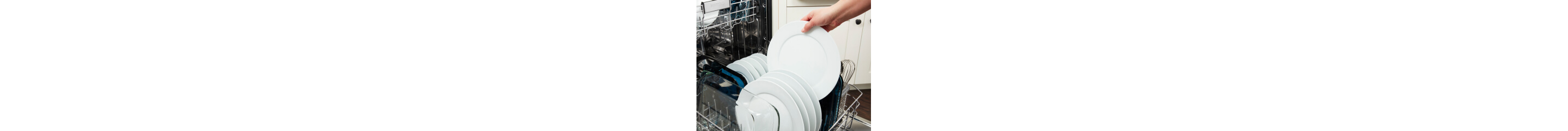 A hand loading a white plate into a dishwasher rack