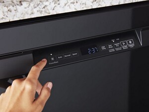A hand operating the controls of a front control dishwasher