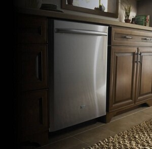 A stainless steel dishwasher with a bar handle surrounded by wood cabinetry