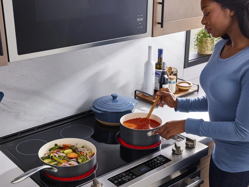 A woman stirring tomato sauce on a stovetop