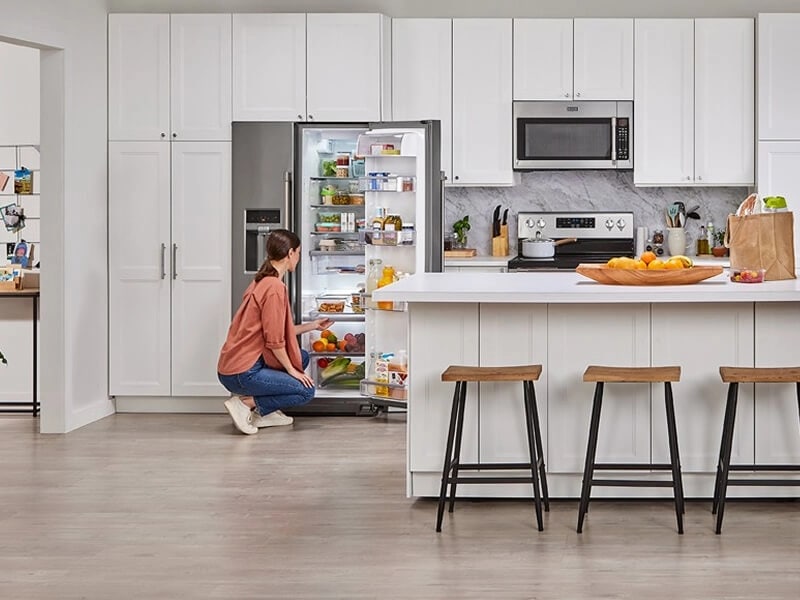 Person using a crisper drawer in a Maytag® side-by-side refrigerator