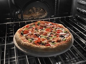 A supreme pizza baking on a pizza stone on an oven rack