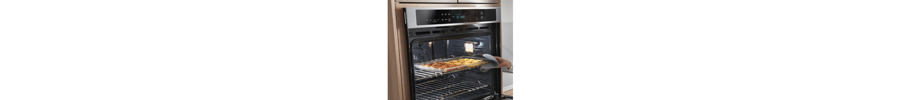 Hand holding an oven mitt sliding in a baking sheet into the oven