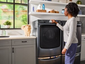 Person setting washer settings with cat on counter next to washer