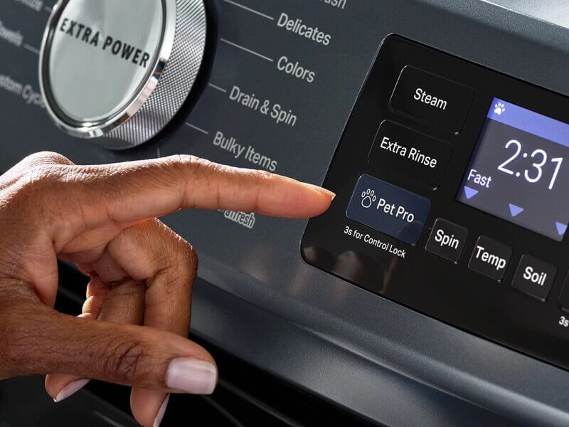 A finger readying to press a Pet Pro Cycle button on a washer control panel