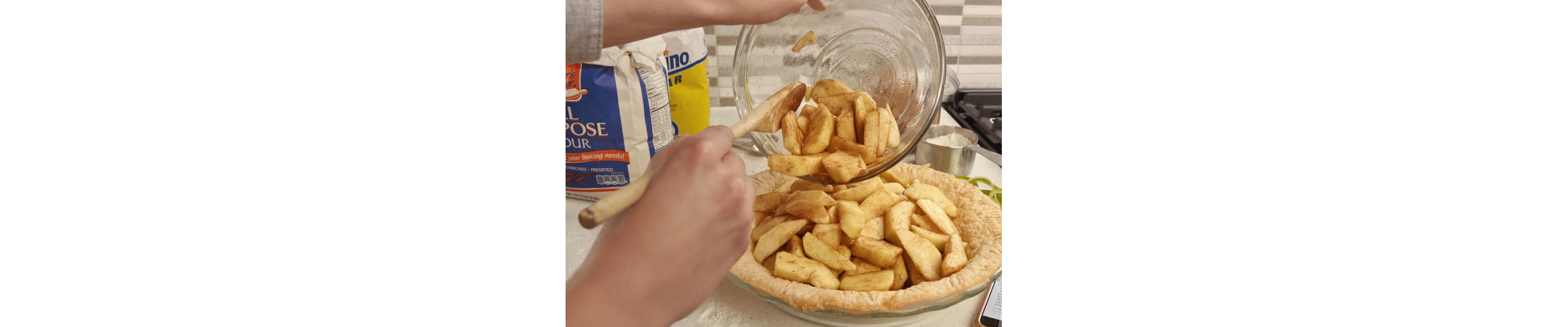 Hand preparing a pie with apple slices