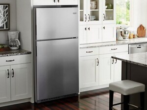 Stainless steel top freezer refrigerator in a kitchen with white cabinetry and grey granite countertops