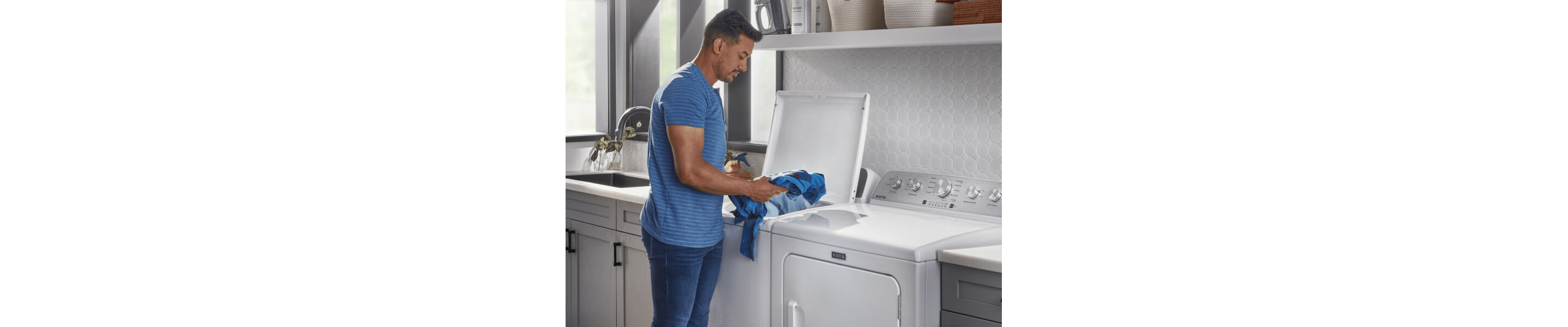 Person loading clothes into a white Maytag® top load washer