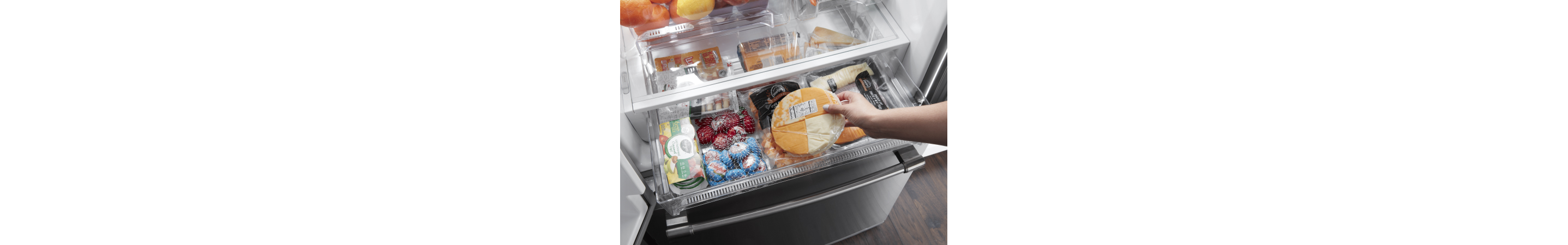 Person loading food into a refrigerator drawer