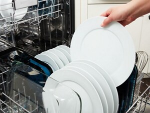 A hand loading a dish into a dishwasher