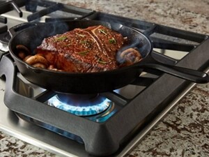 Steak in a skillet with mushrooms on a gas cooktop