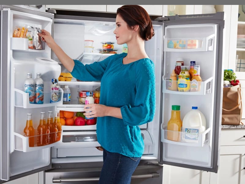 Person loading food into French door refrigerator