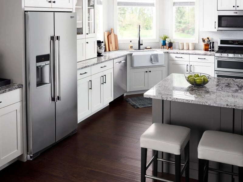 Counter-depth side-by-side refrigerator in kitchen with white cabinets