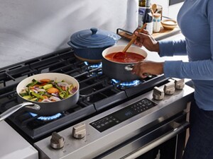 A person cooking tomato sauce on a gas stove