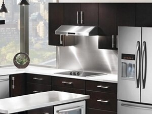 A view of a kitchen with dark wood cabinetry, a small island with a beverage fridge in the middle, a French door refrigerator, sink, and a stainless steel under-cabinet range hood over a cooktop