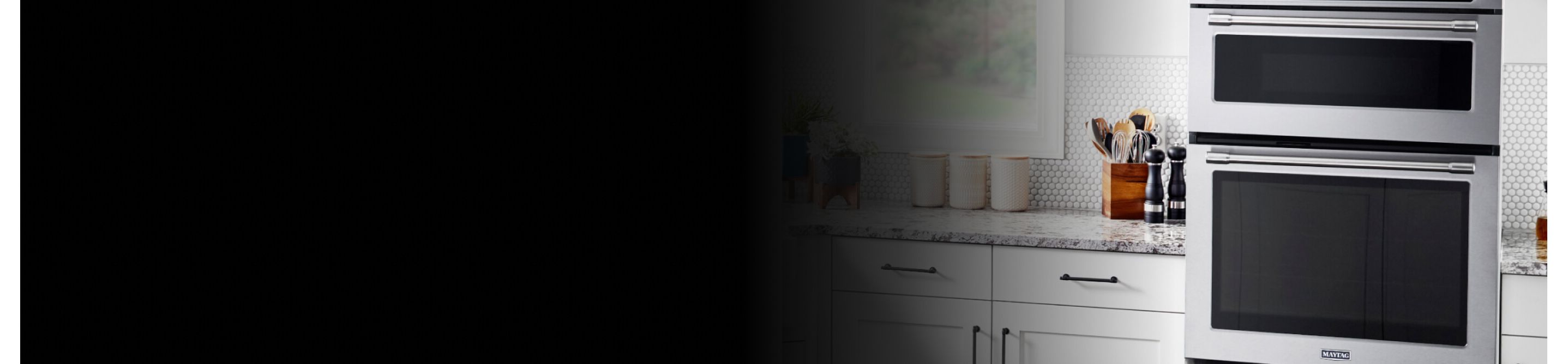 A Maytag® wall oven microwave combo placed between white cabinets with gray countertops