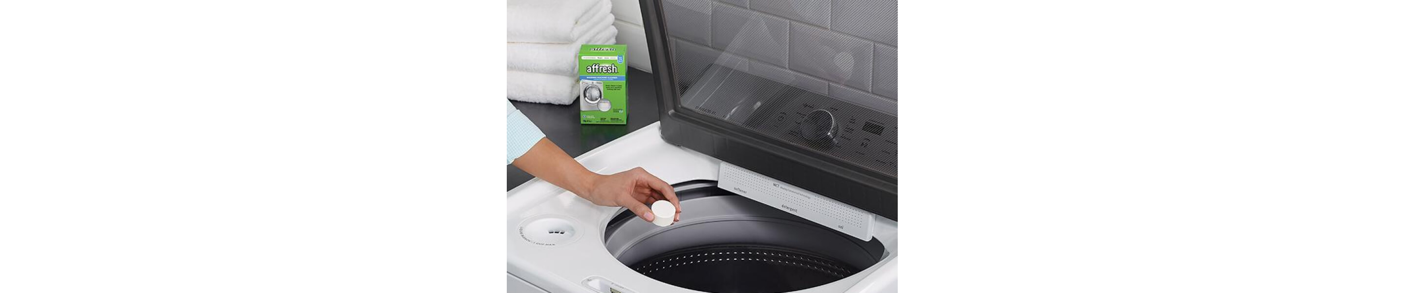 Person placing an affresh® washing machine cleaning tablet into a top load washer drum