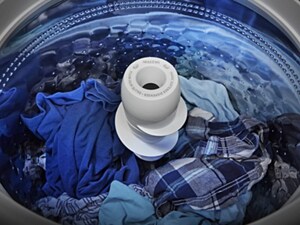 A washer drum with an agitator, full of clothing