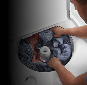 A person putting laundry in their washing machine