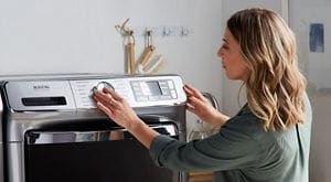 A woman setting a laundry cycle on a Maytag® washing machine