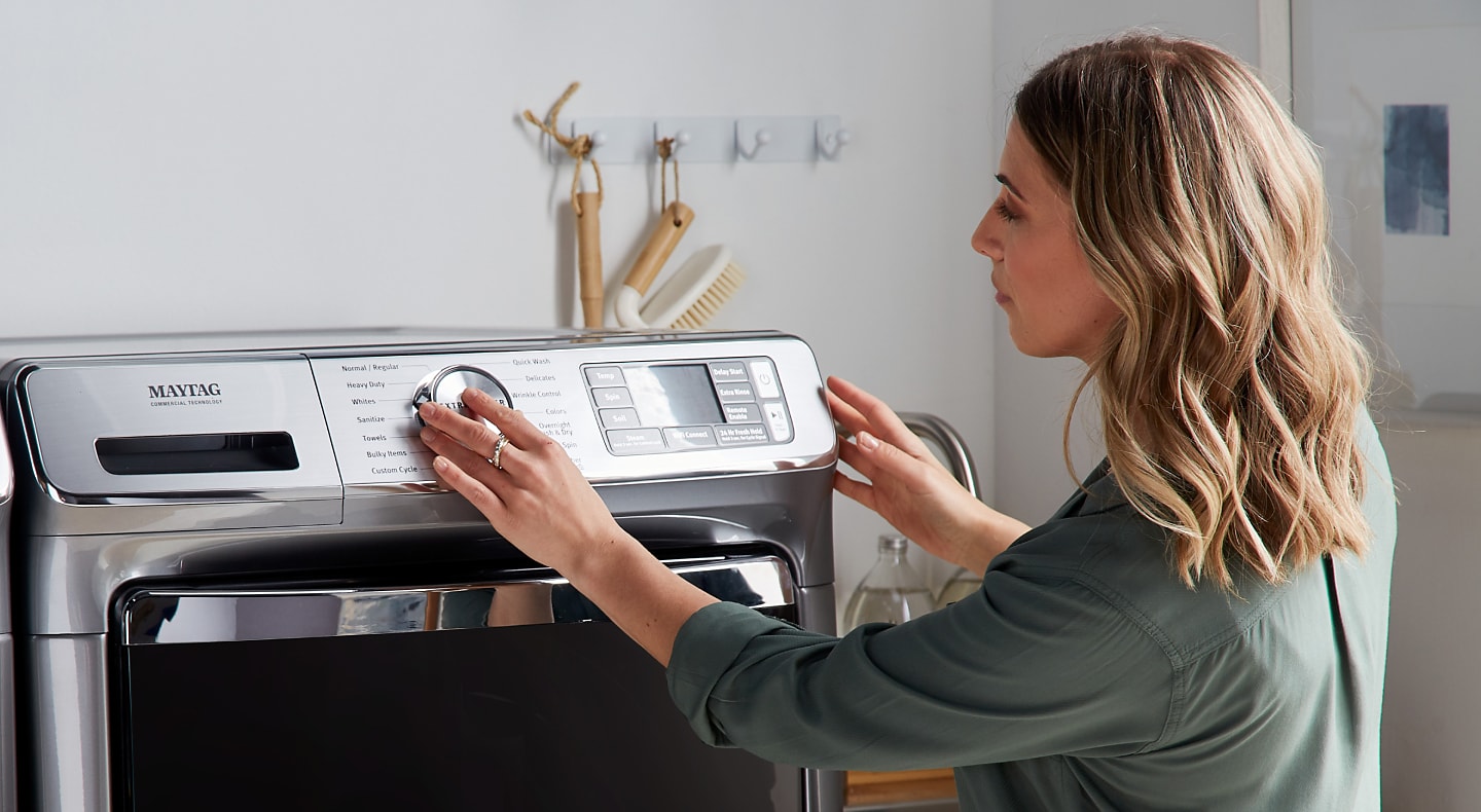 A woman setting a laundry cycle on a Maytag® washing machine