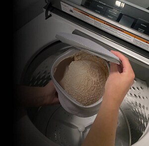Person holding mesh laundry bag over open washer
